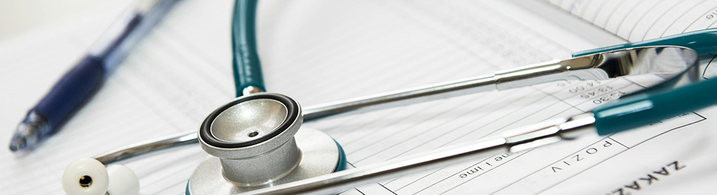 Close up of a stethoscope and blue pen lying on a book.