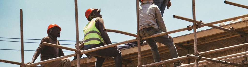 Construction workers with hardhats sitting on scaffolding in the sun