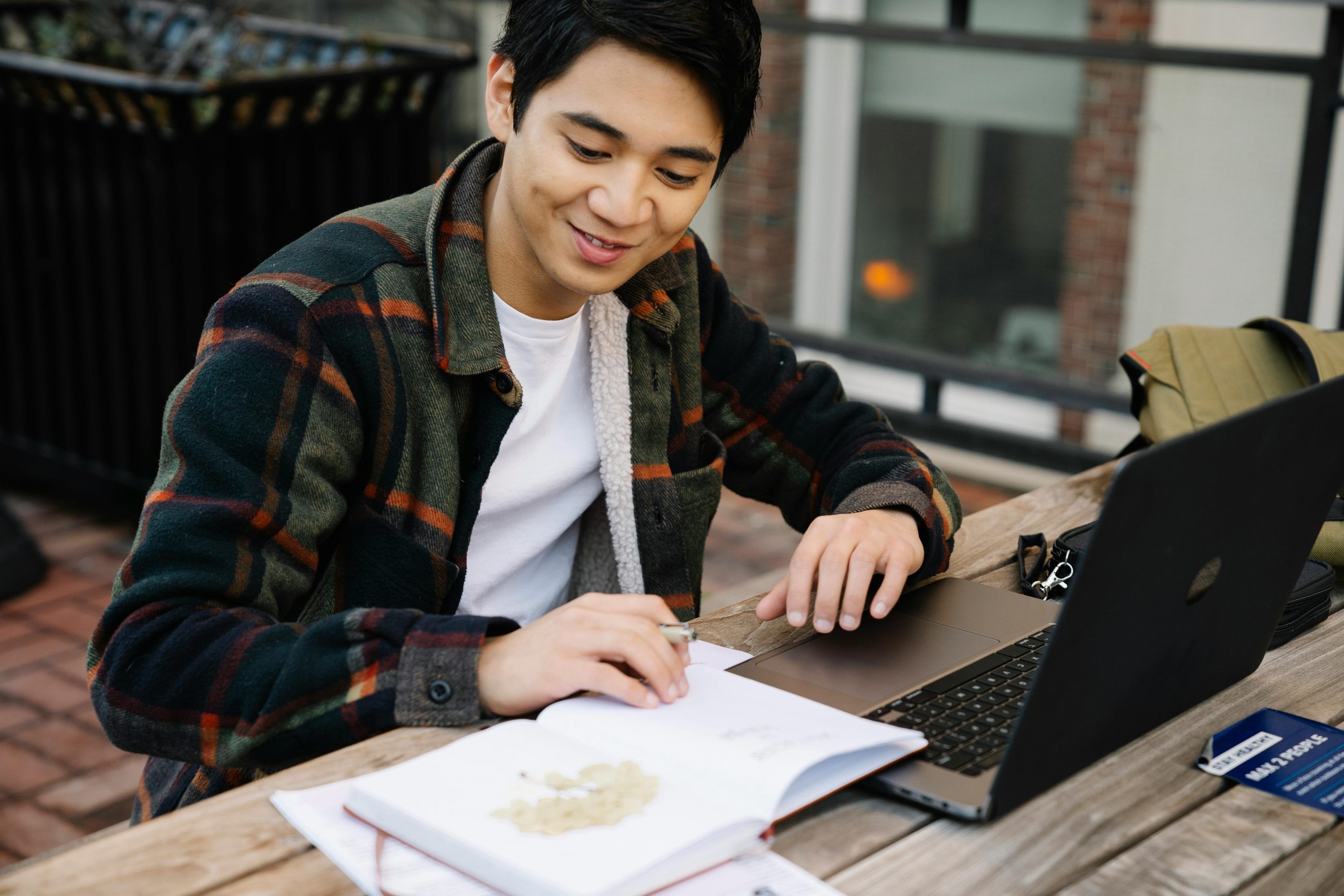 Guy Sitting at Table Outdoors Working on Laptop